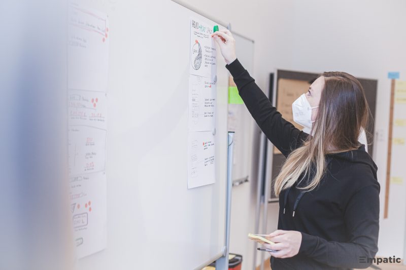 A design workshop participant placing post-its on a whiteboard.