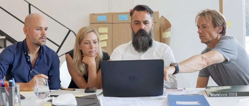 Four Swarovski employees collaborating around a laptop during a design workshop.