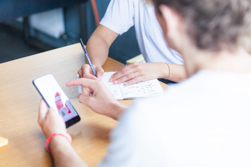 Two UX Designers analyzing a mobile app and taking notes.